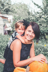 Fototapeta premium Halloween. Daughter hugging mother near jack-o-lantern in the garden. Decoration for party. Happy family. Toned photo.