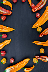 Mixed of half red and yellow pepper with a green branch near cherry tomato on  black backround. Top...