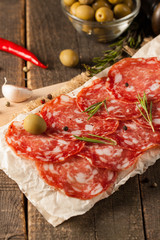 Chorizo sausage and salami, thin cut. spanish salami on the wood background with spices, paprika, pepper. Spicy food. Chili.