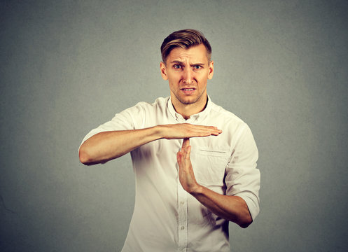Young angry man showing time out hand gesture
