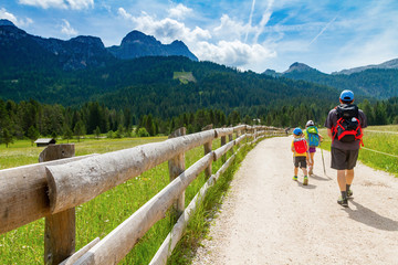 Fototapeta na wymiar Dolomites Italy, family walking along a mountain path in a sunny