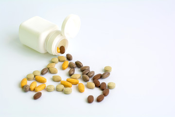 Different drugs and health supplement pills from a medicine bottle on white background , selective focus , copy space.