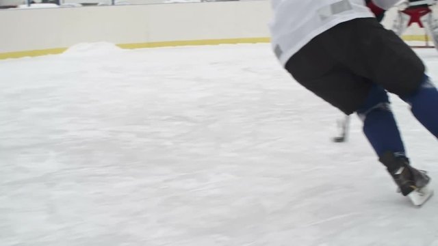 Tracking rear view of forward player dribbling puck with stick then scoring goal and celebrating while goaltender protecting teams net with butterfly technique in slow motion