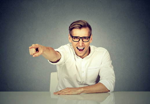 Angry businessman sitting at his desk and screaming