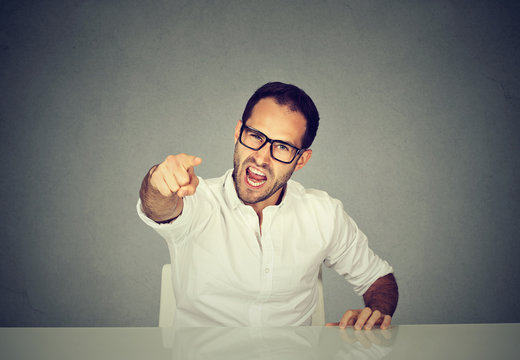 Angry businessman sitting at his desk and screaming