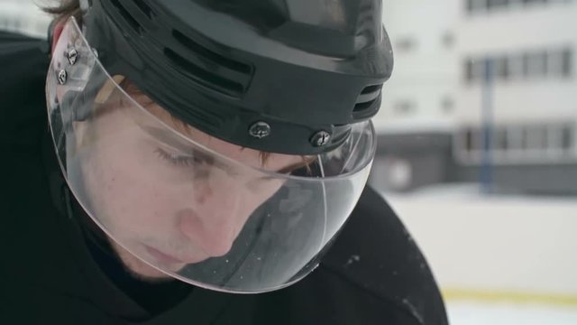 Slow motion close up of face of determined hockey player in protective helmet getting ready for dribbling puck during drill in outside ice rink