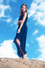 Beautiful young woman posing on a background beaurtiful sky with clouds