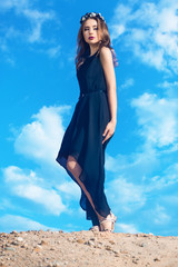 Beautiful young woman posing on a background beaurtiful sky with clouds