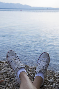 Female feet in sneakers on the background of a sea © nikodash