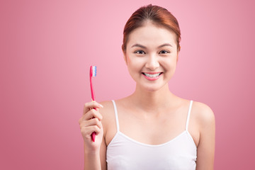Smiling young woman with healthy teeth holding a tooth brush ove