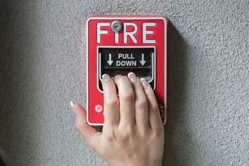 Hand pulling down the fire alarm button

