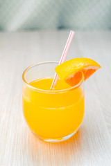 Some orange juice with straw into glass for breakfast.