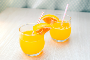 Some orange juice with straw into glass for breakfast.