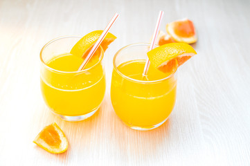 Some orange juice with straw into glass for breakfast.
