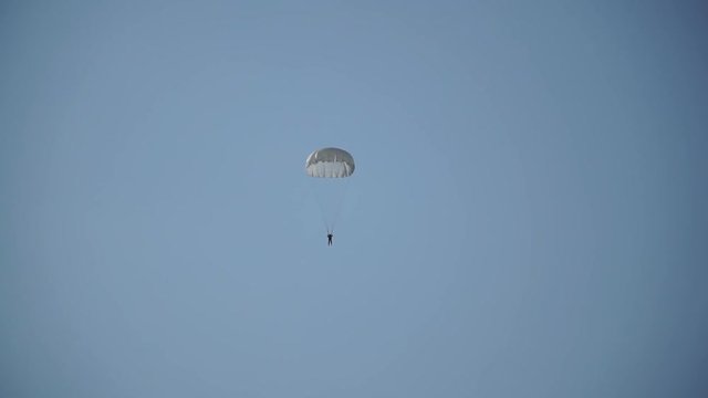 paratrooper in the sky, blue sky, white parachute