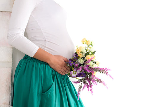 pregnant belly with flowers in a green skirt and a white jumper
