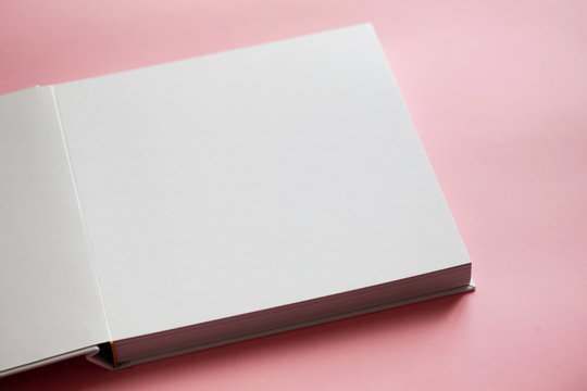 Part of white empty open book on pink background