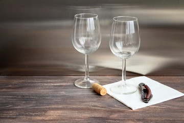Wine glasses on wooden table. Composition with cork, wine opener, special light. Copy space,