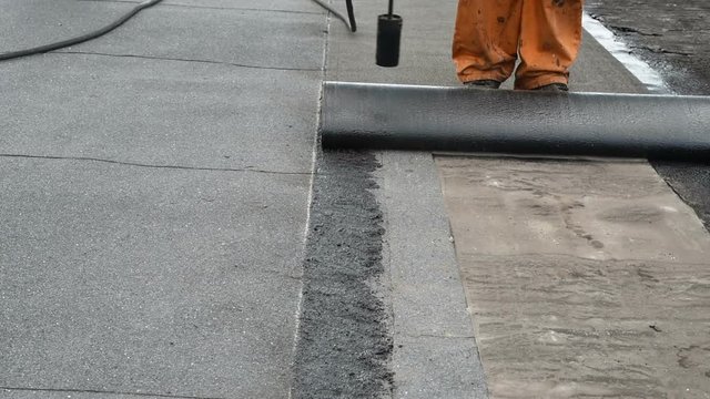 Roofer doing repair waterproofing flat roofs.
