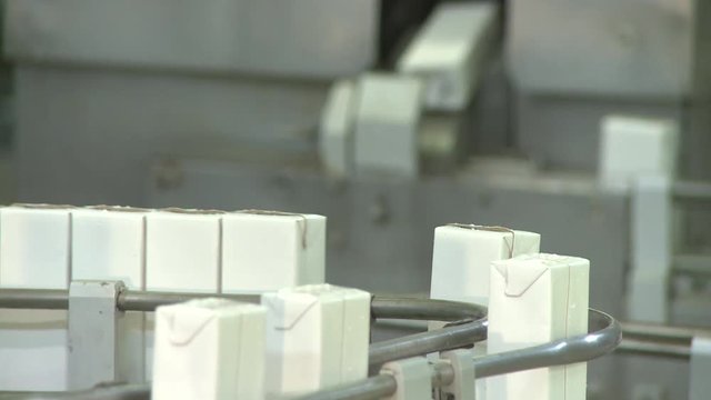 Automated machine processes milk, milkshake and juice boxes in a factory
