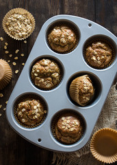 Healthy wholewheat and oatmeal muffins, served in a baking tin, vertical shot, overhead view