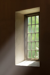 Fototapeta premium Light beams shining through glass window panes and across dark brown wall
