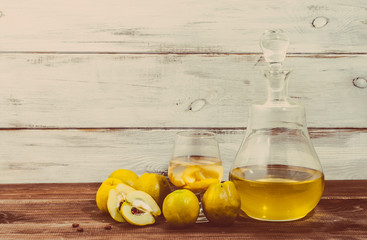 Vintage bottle of liquor on rustic wooden table. Homemade alcohol made from fruit of quince
