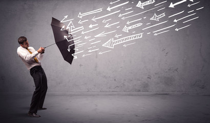 Business man standing with umbrella and drawn arrows hitting him