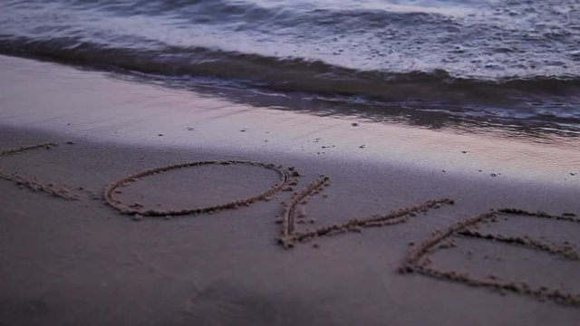 Love drawn jn beach sand washed away by waves