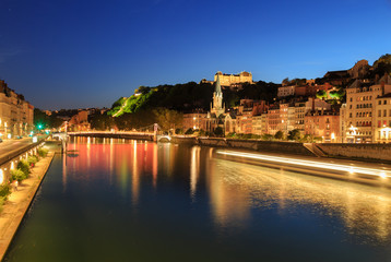 Fototapeta premium Boat sailing in the Saone river toward Passerelle Saint Georges, in Lyon city.