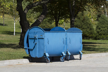 Two blue garbage containers at park