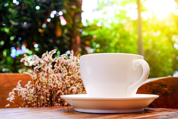 White coffee cup with dry flower on wooden table.Focus coffee wi