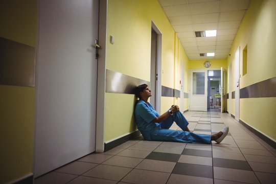 Depressed nurse sitting in hospital corridor
