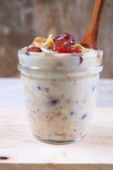 Close up of a jar of Muesli with dried fruit, nuts and bananas on a wooden table.