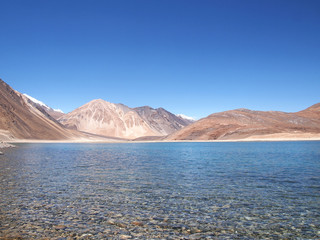 View of Pangong Lake with mountains and crystal clear water in the background in Leh, Ladakh, the north of India.