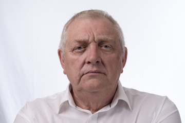 Close up portrait image of a mature man looking annoyed and angry. Taken on a white background. 