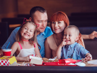 Happy family eating fast food in restaurant all together