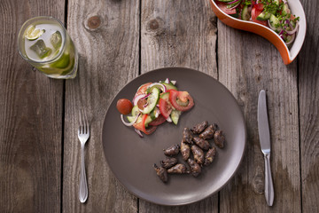 "Churrasco de curacao",traditional Brazilian barbecue, grilled chicken hearts composition with tomatoes and onion salad an old wooden table.