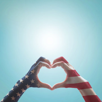 American flag pattern on people hands in heart shaped form against vintage sky background w/ clouds: Memorial day Happy columbus day Patriot day, USA Independence Labor Loyalty day symbolic concept.