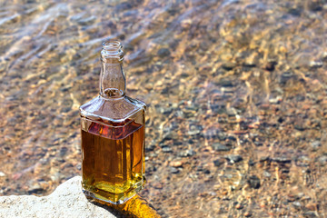 Bottle whiskey on stone near river