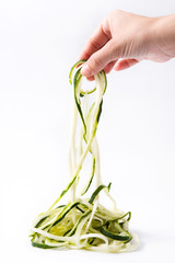Hand taking zucchini noodles isolated on white background

