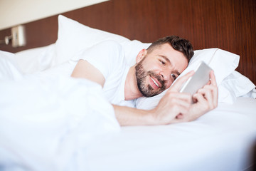 Man texting his girlfriend in bed