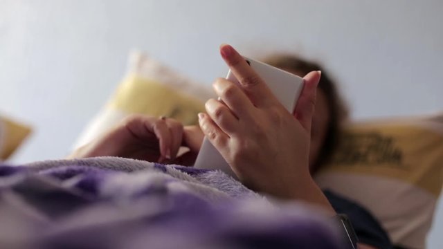 Woman Lying In Bed Reaching To Check Mobile Phone