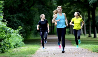 Papier Peint photo Lavable Jogging Junge Frau läuft mit Freundinnen im Park