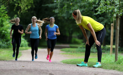 Geschafft - Junge Frau stützt sich auf den Oberschenkeln nach dem Lauftraining ab