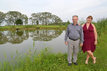 The married couple costs on the bank of a pond in summer day