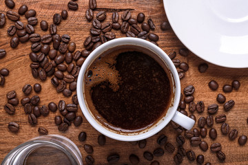 cup of coffee on table covered with coffee beans