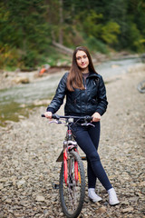 Fototapeta na wymiar Attractive young girl with bike near river in forest