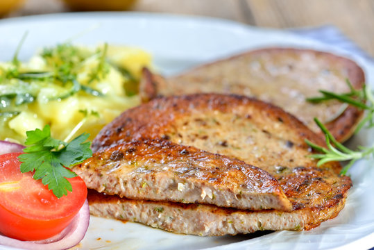 Eine bayerische Spezialit&auml;t: Gebratene Milzwurst mit Kartoffelsalat - Bavarian food: Fried sausage with pieces of spleen served with potato salad