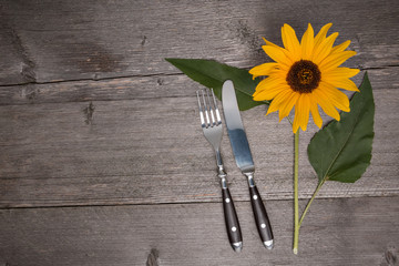 Besteck und Sonnenblume auf einem alten Tisch